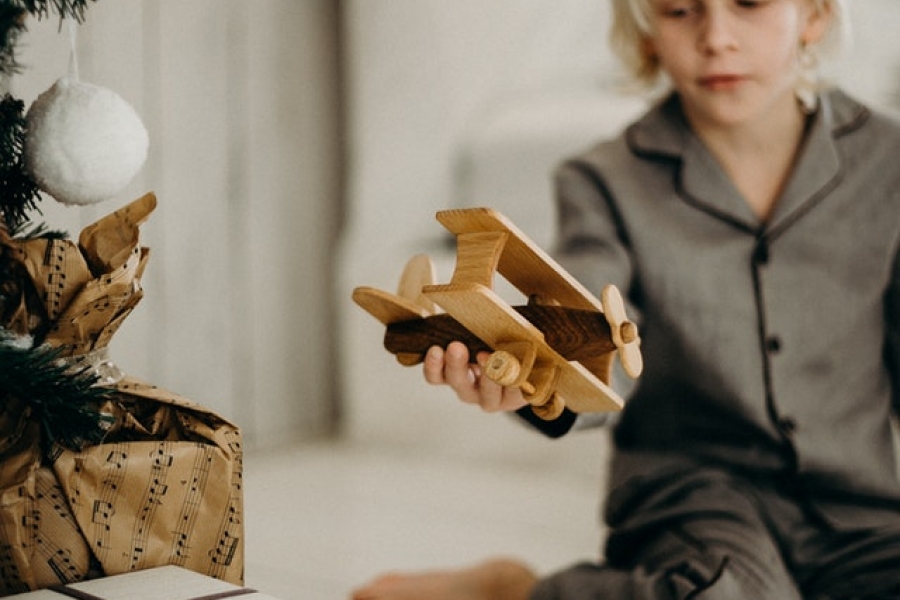 boy-in-gray-pajamas-holding-brown-wooden-plane-toy Boy in gray pajamas holding a wooden plane toy