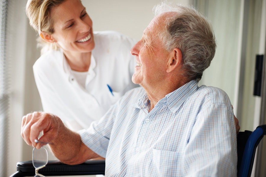 Palliative Care Nurse smiling at elderly on wheelchair