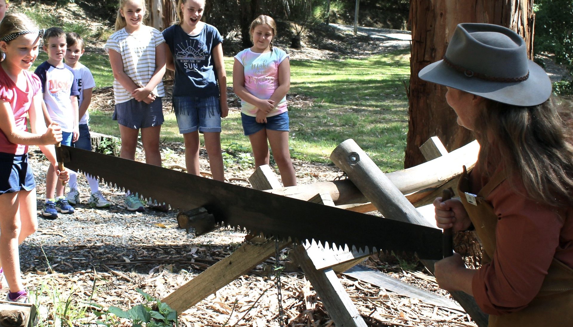 Images courtesy of South Gippsland Shire Council Image of a woman demonstrating an old saw while a group of young children watch