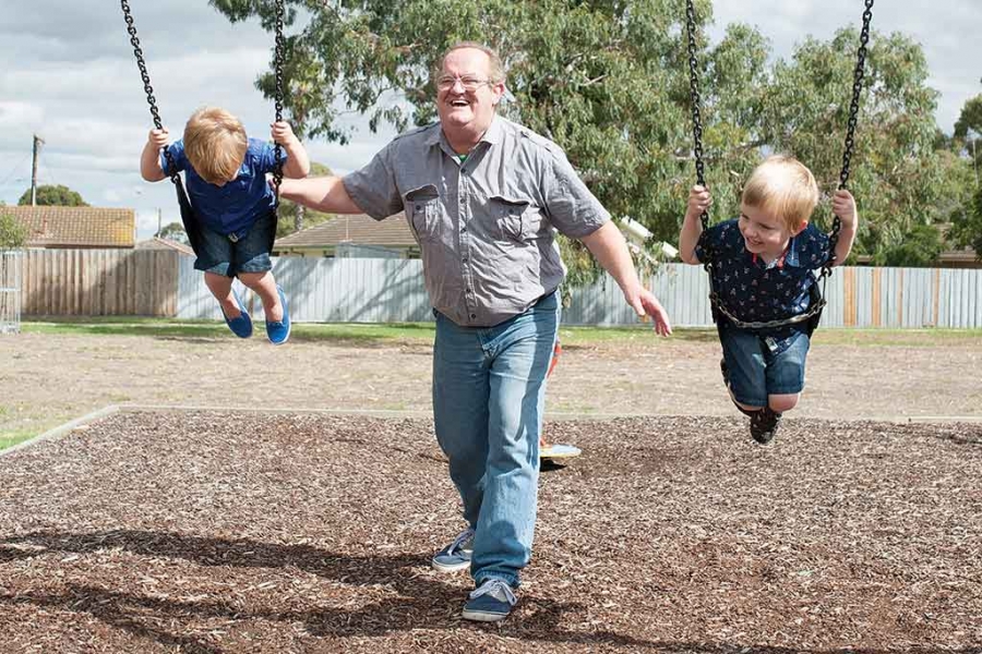 Grandad playing with grandkids on swing