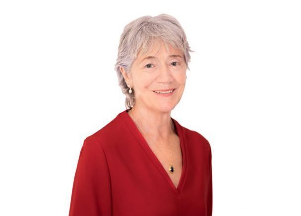 Judith Headshot of board member Judith Walker, smiling wearing a red blouse and a gold necklace with a black pendant
