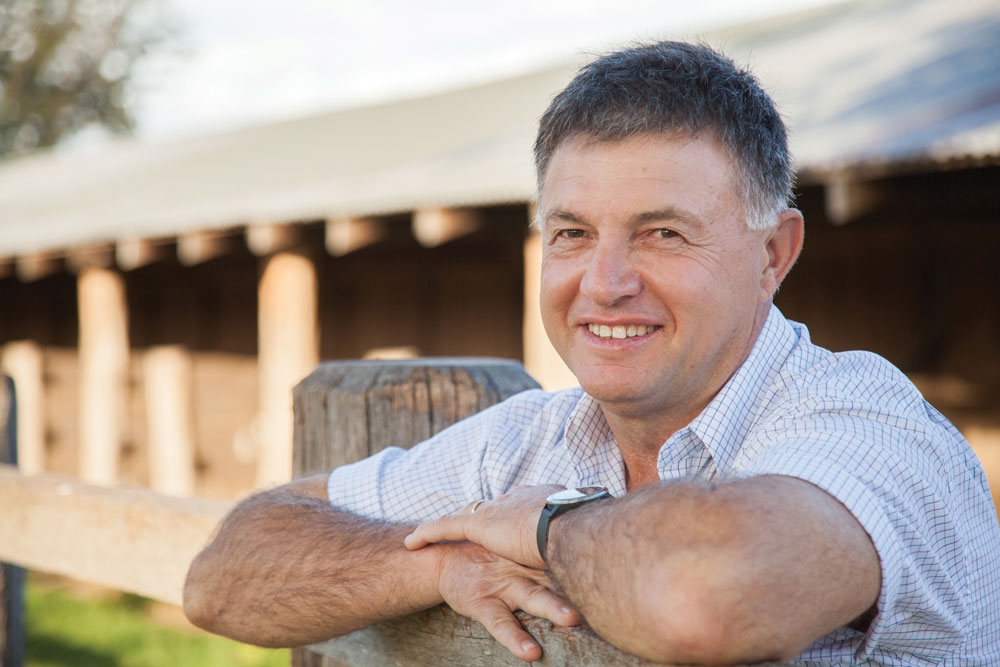 A man leans against a fence post, smiling. A man leans against a fence post, smiling.