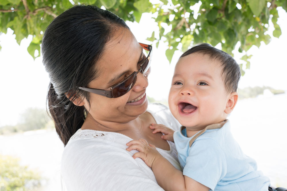 A woman holds her giggling baby in her arms.