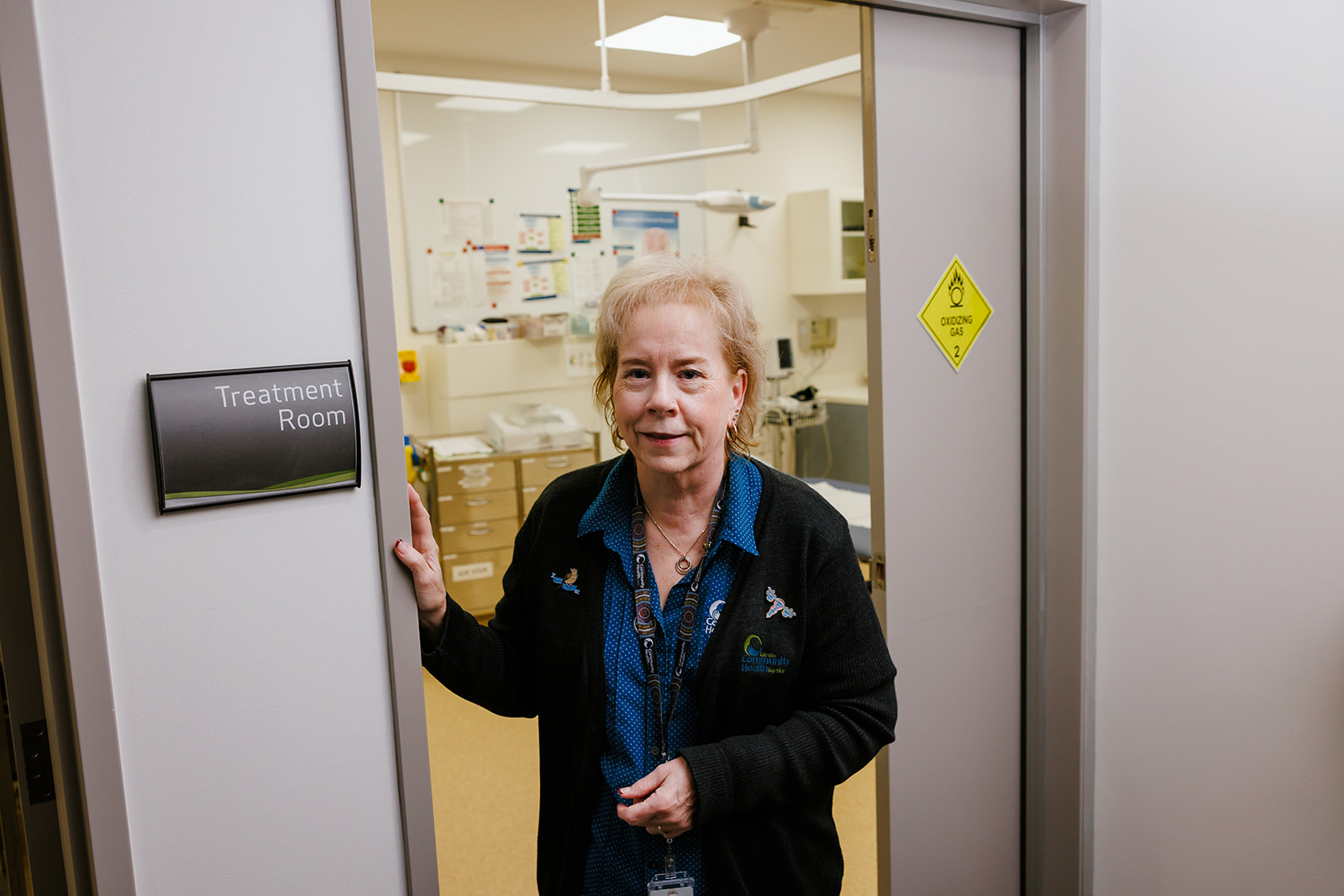 A nurse standing in the doorway of a treatment room