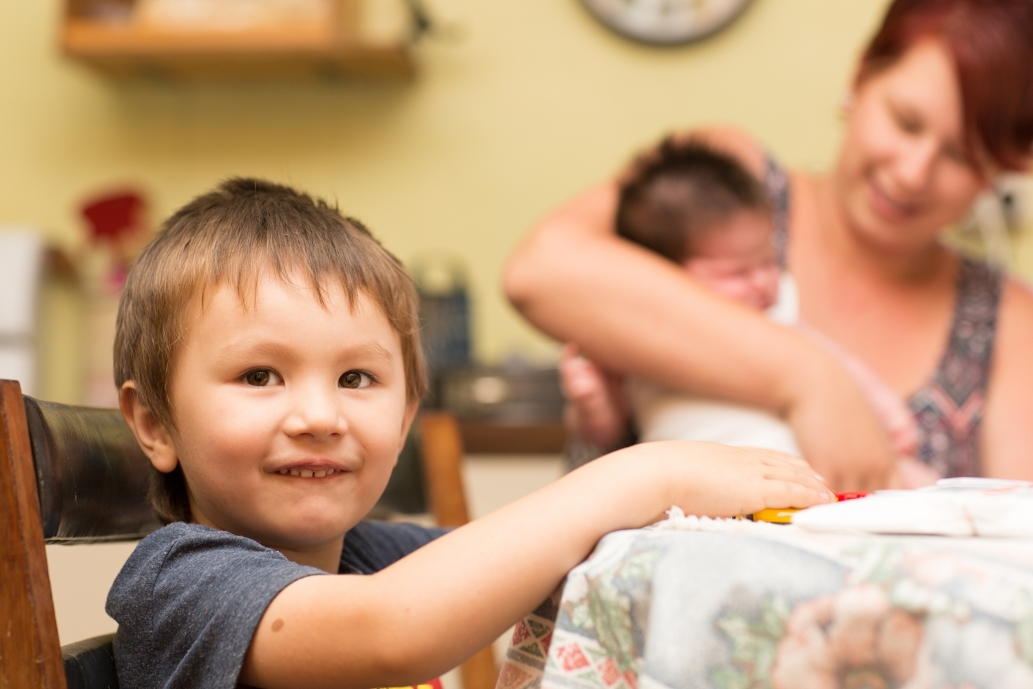 Families (10) Small child sitting at a table smiling