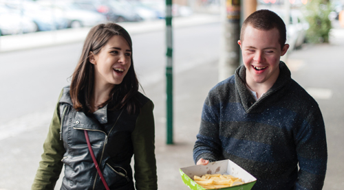 Girl and boy walk down street, laughing and eating hot chips. Girl and boy walk down street, laughing and eating hot chips.