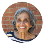 A senior women with shoulder length grey hair smiles at the camera